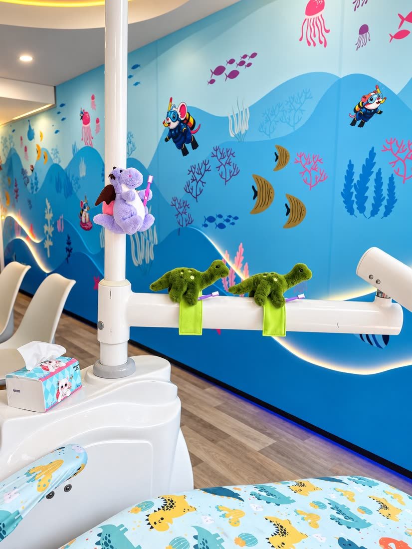 Sillón dental infantil del consultorio, con mural de fondo marino y peluches